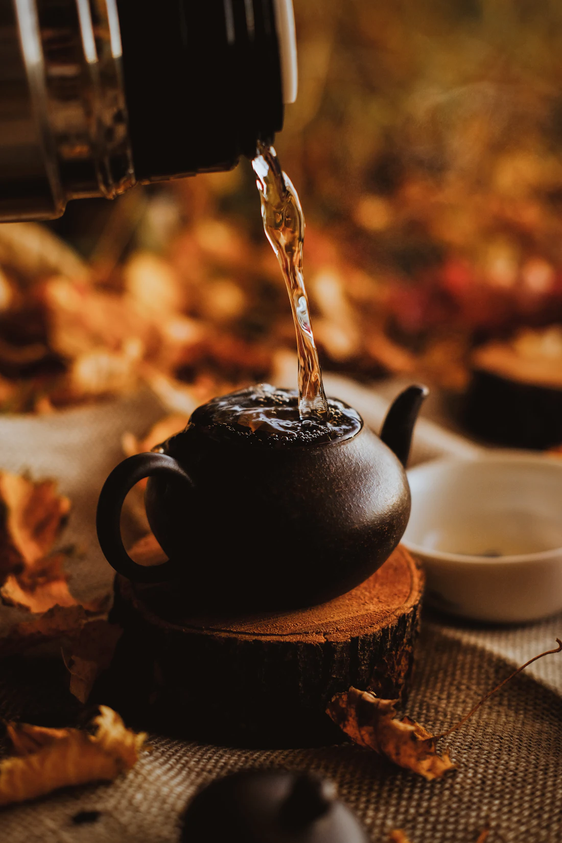 Hot water being poured into a dark clay pot for brewing herbs