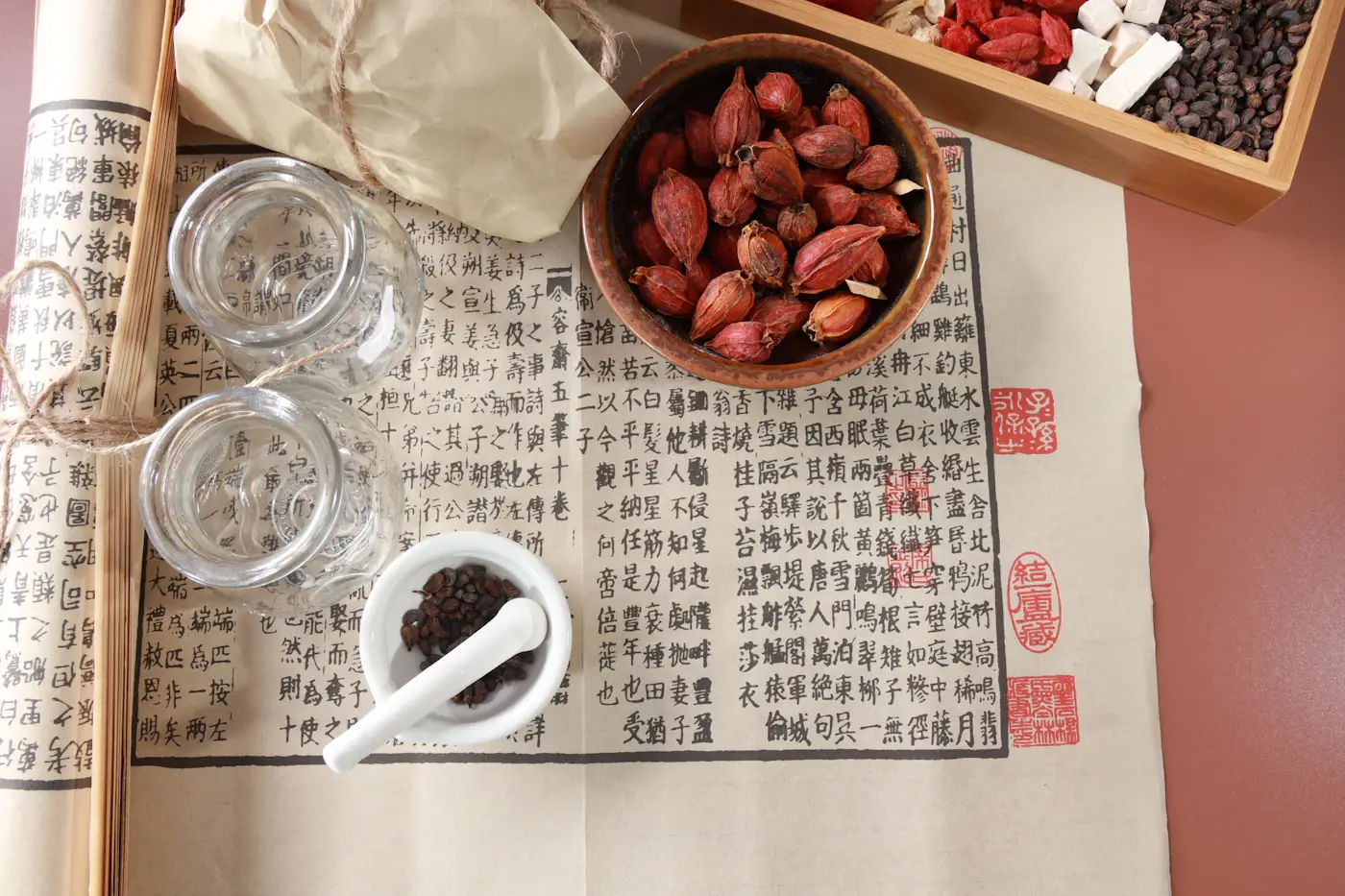 Classical Chinese medicine text with glass jars, a mortar and a bowl of dried herbs