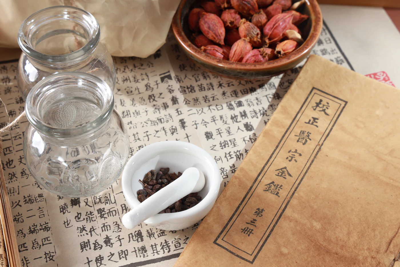 Classical Chinese formula text beside glass jars, a ceramic cup and a bowl of dried rosebuds