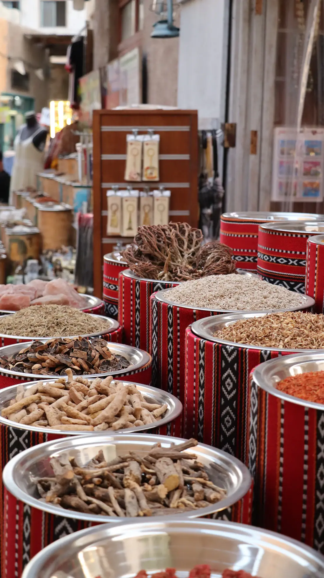 Bowls of dried Chinese herbs and sliced roots displayed at a traditional market stall