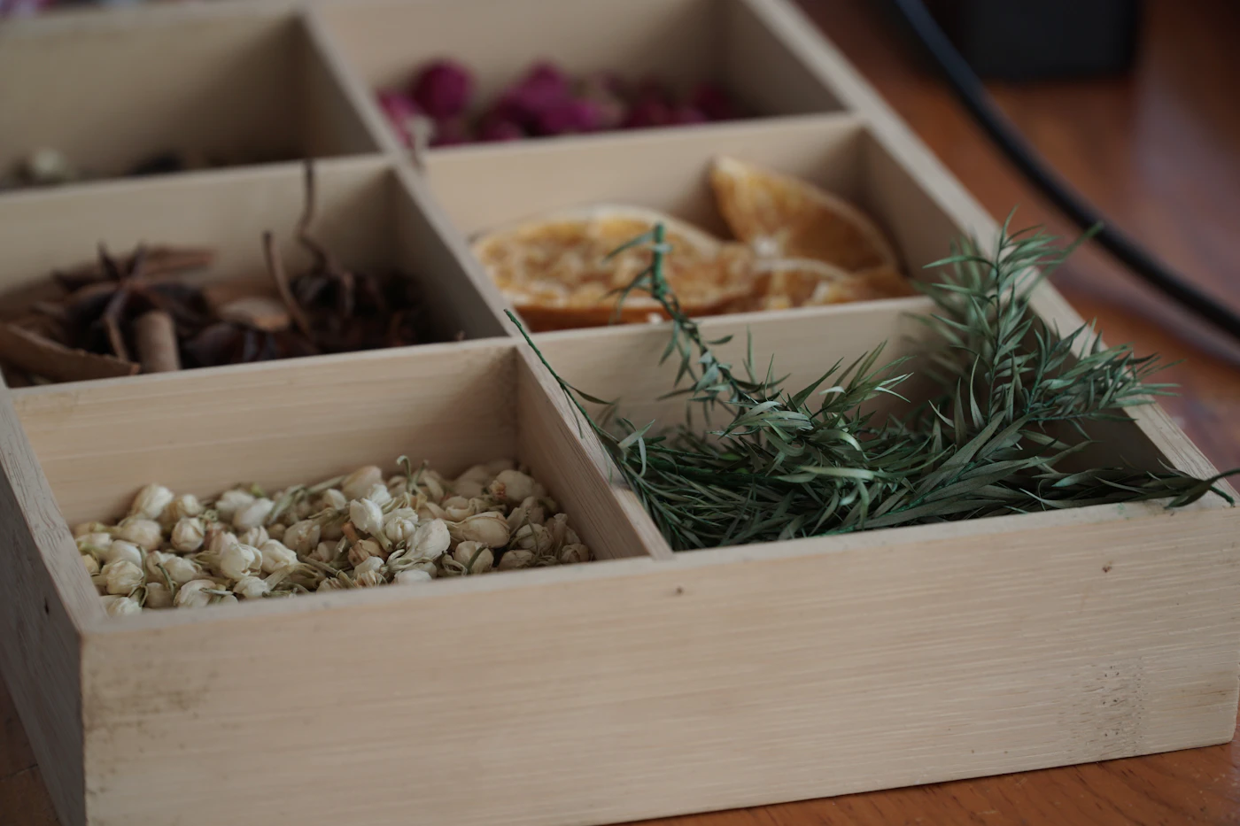 Wooden box with compartments of dried herbs, flower buds, citrus peel and seeds