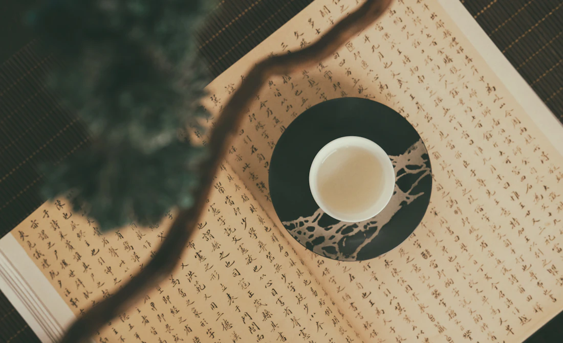 Cup of herbal tea resting on an open classical Chinese medicine text
